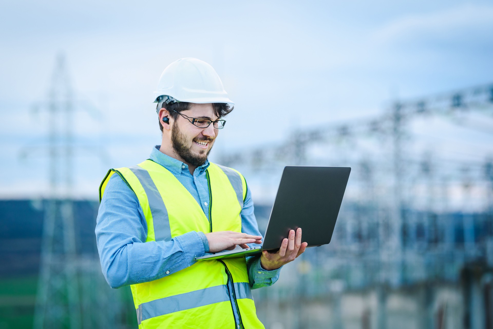 Ingeniero eléctrico trabajando en un ordenador portátil frente a la foto de stock de la central eléctrica