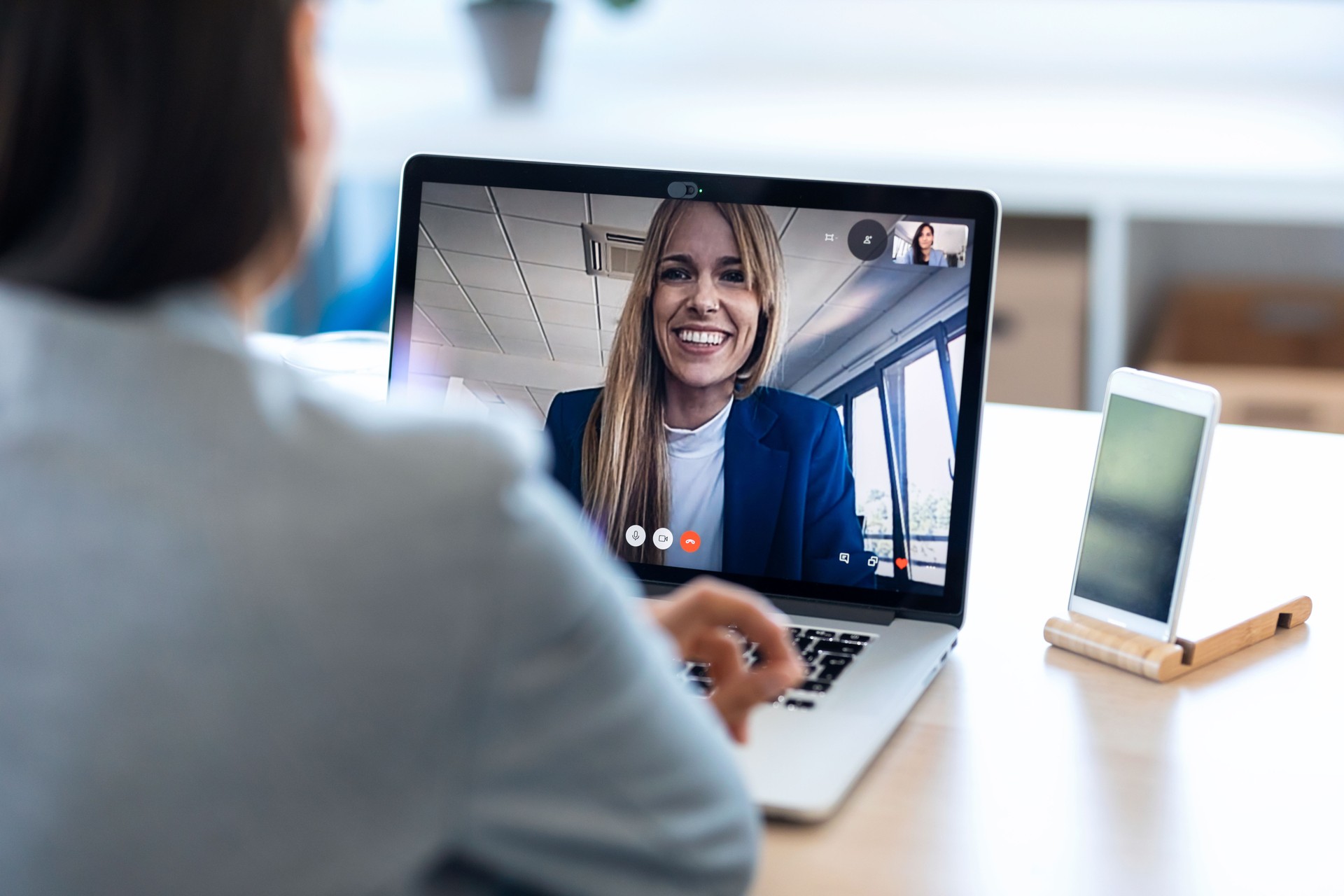 Una empleada hablando en videollamada con su colega en la reunión informativa en línea con computadora portátil en casa.